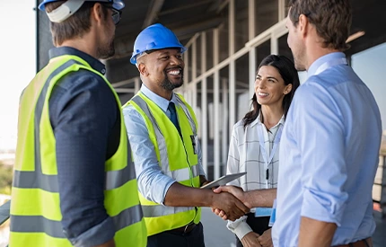 An image of a group of people, some wearing high vis jackets and hard hats, shaking hands